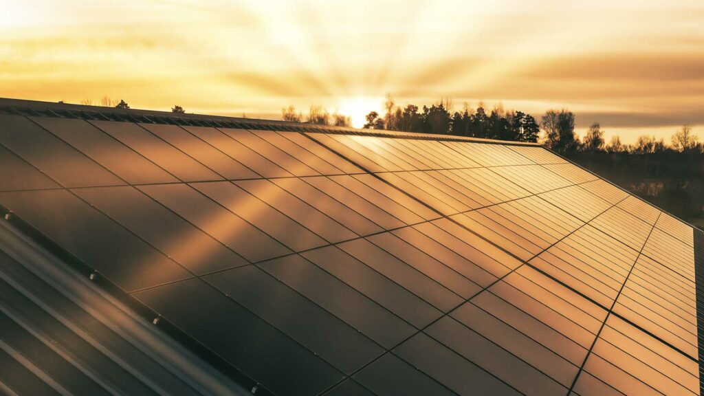 Solnedgång över ett tak med solpaneler på
