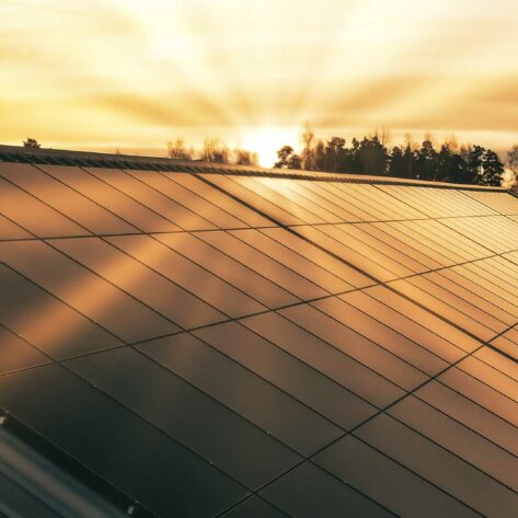 Solnedgång över ett tak med solpaneler på