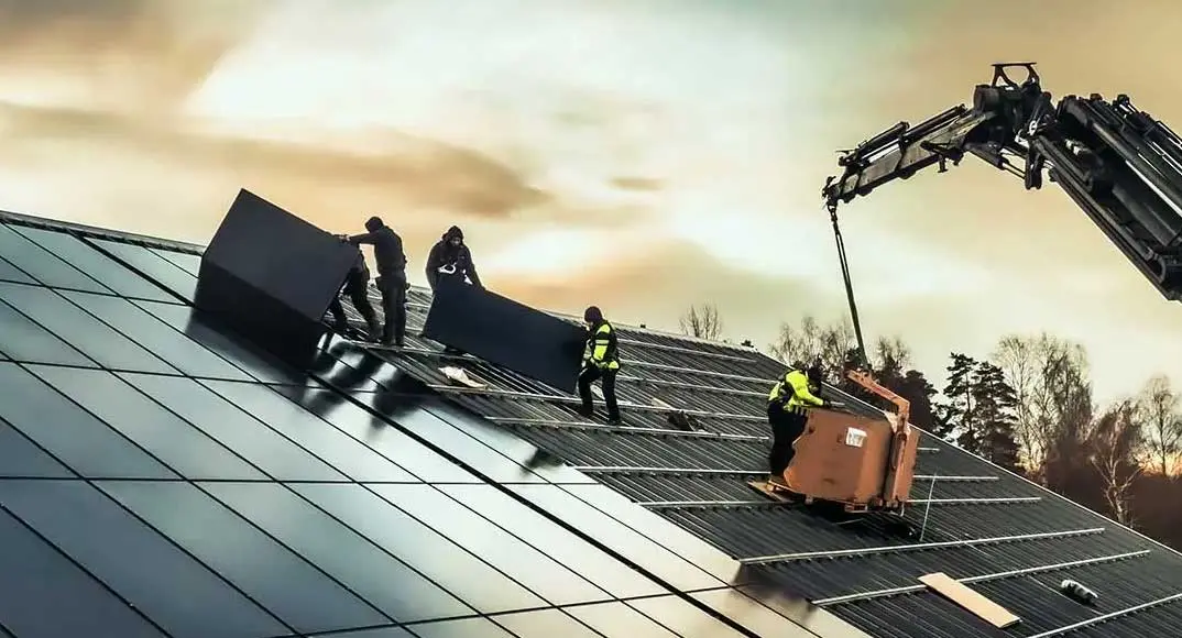 Människor monterar solceller på ett tak i Västerås