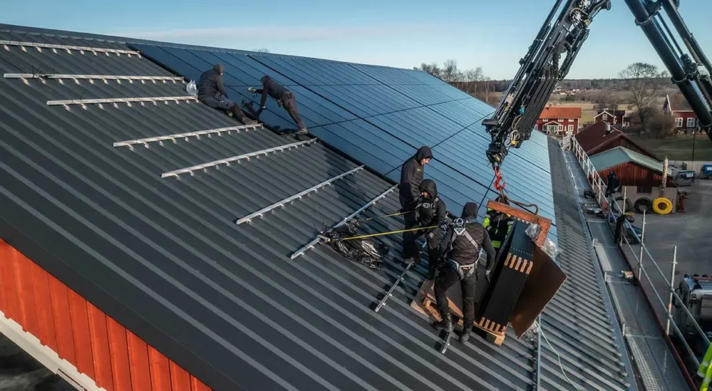 personer på ett tak som monterar solpaneler