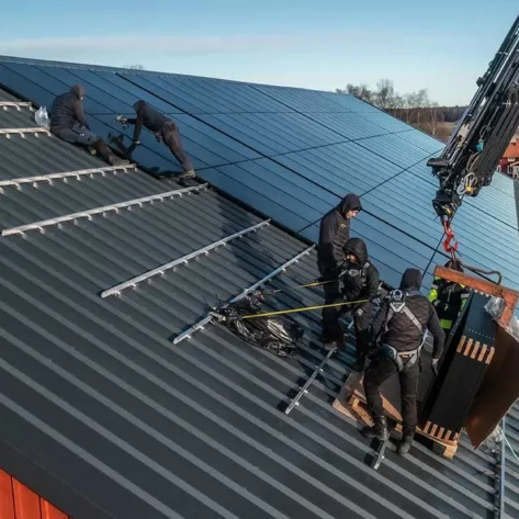 personer på ett tak som monterar solpaneler