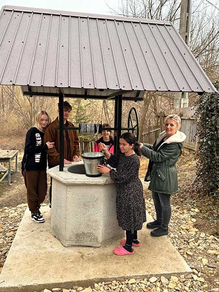 Familj samlad vid en vattenbrunn i Rumänien